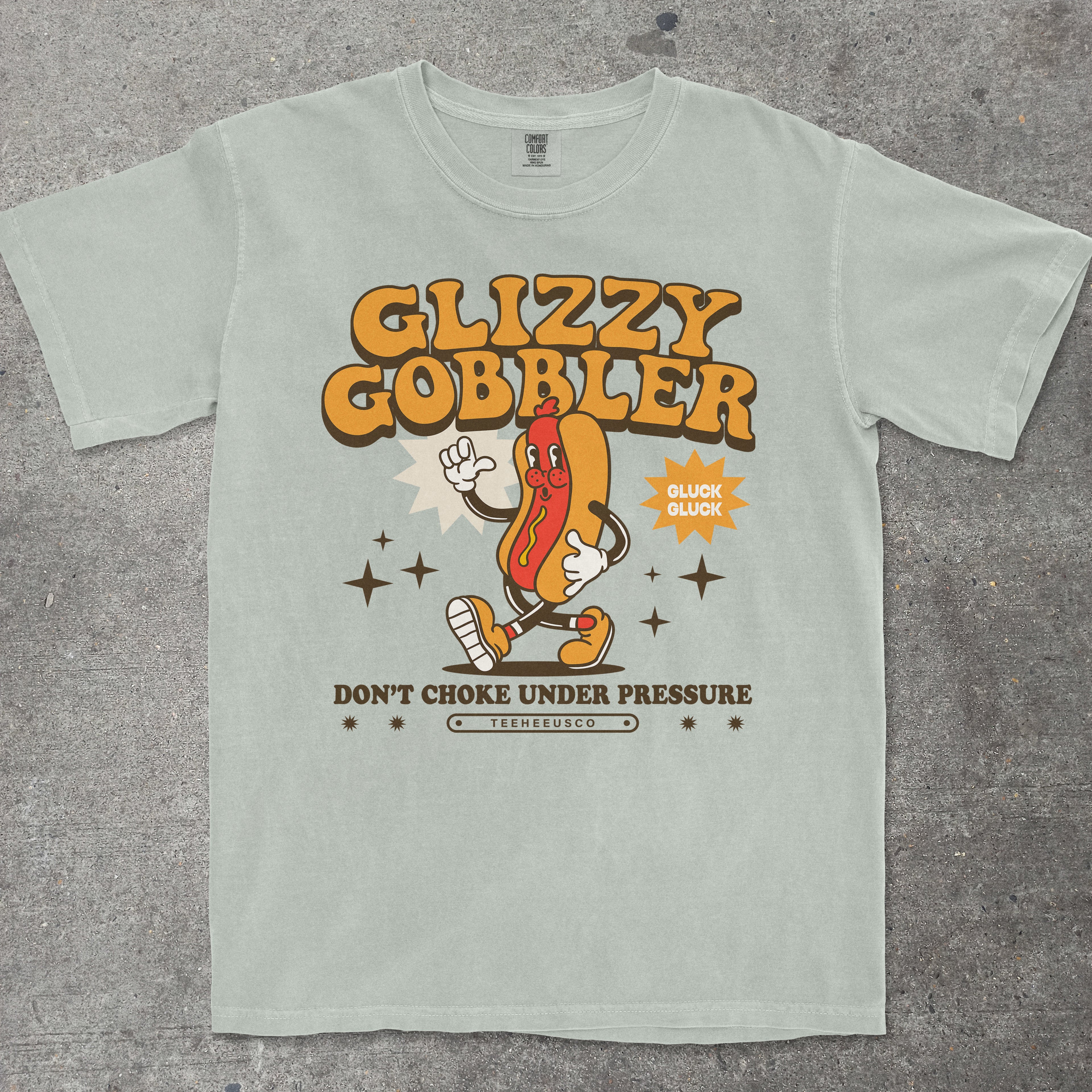 Green t-shirt with 'Glizzy Gobbler' graphic design on a textured gray surface