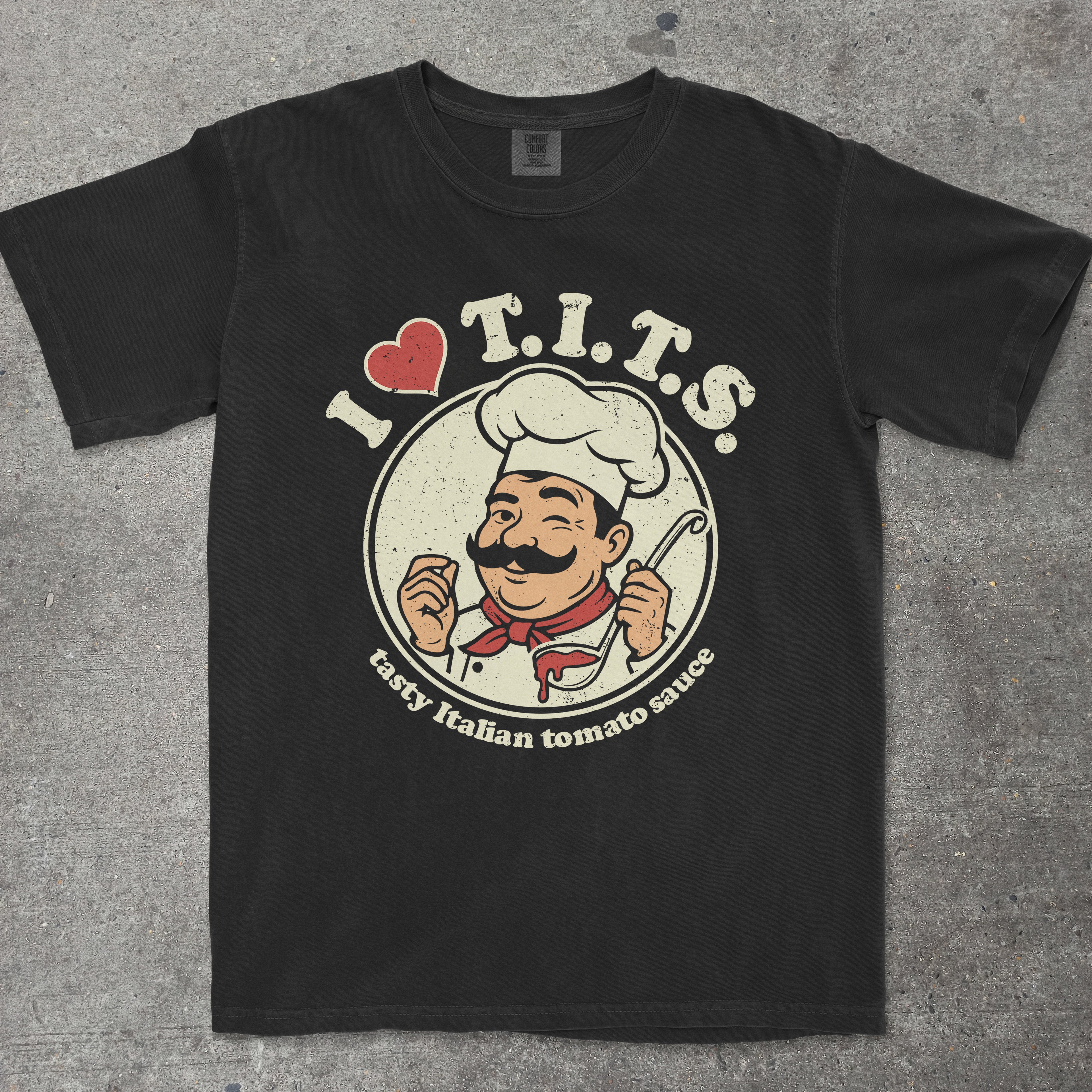 Black graphic tee with retro chef mascot and "I LOVE T.I.T.S." text design by TeeHeeUSCo