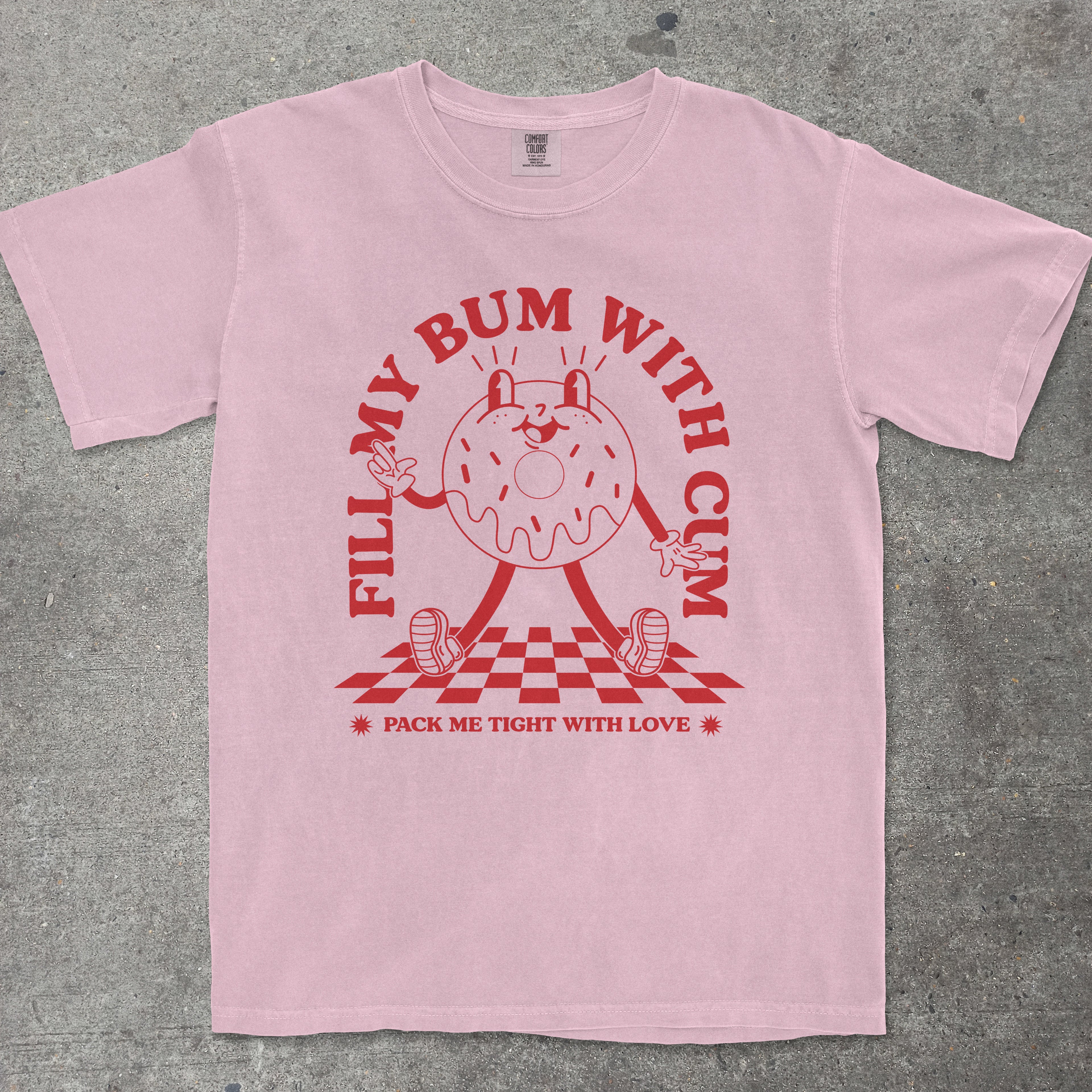 Pink t-shirt with red graphic and text on a gray surface