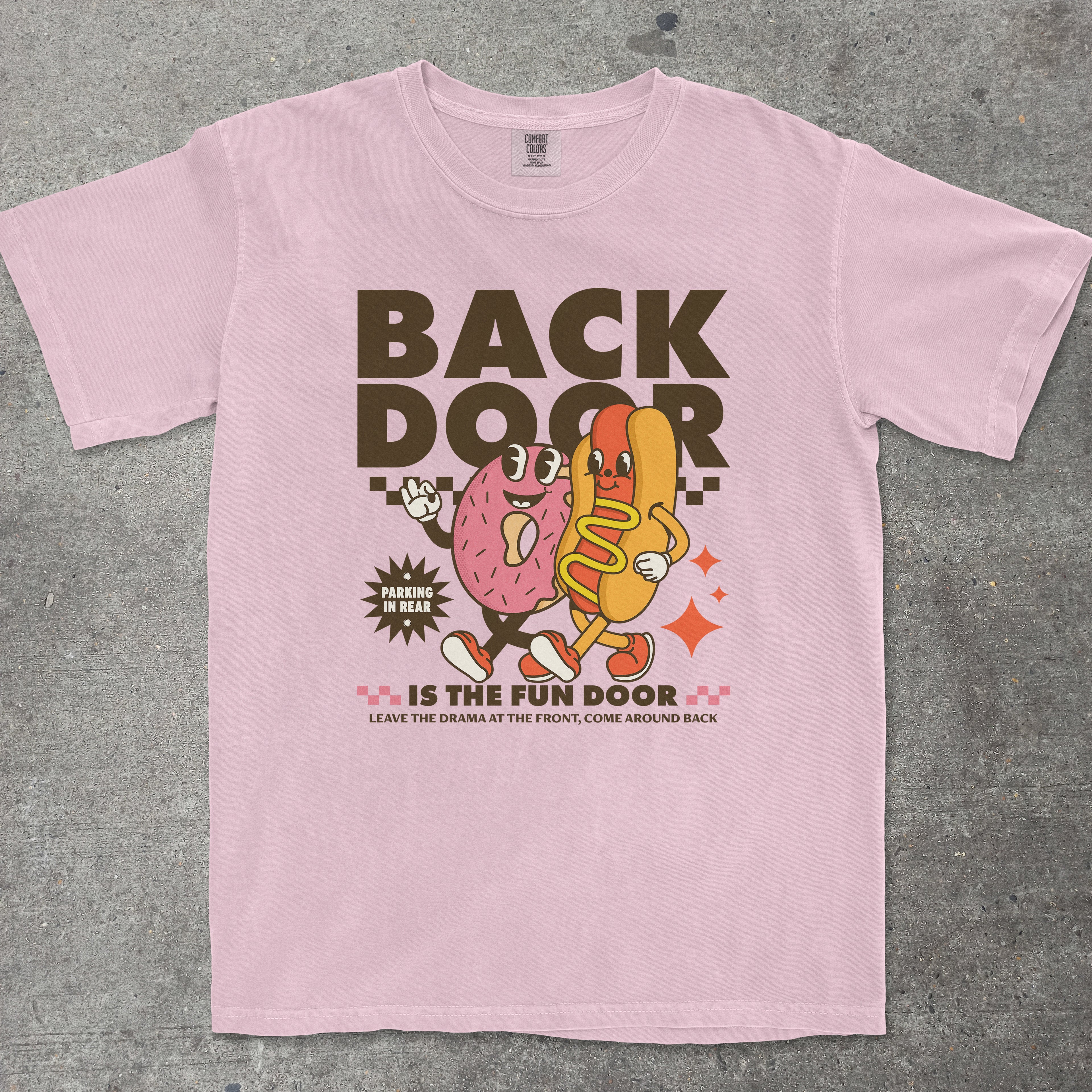 Pink t-shirt with cartoon characters and text on a gray surface