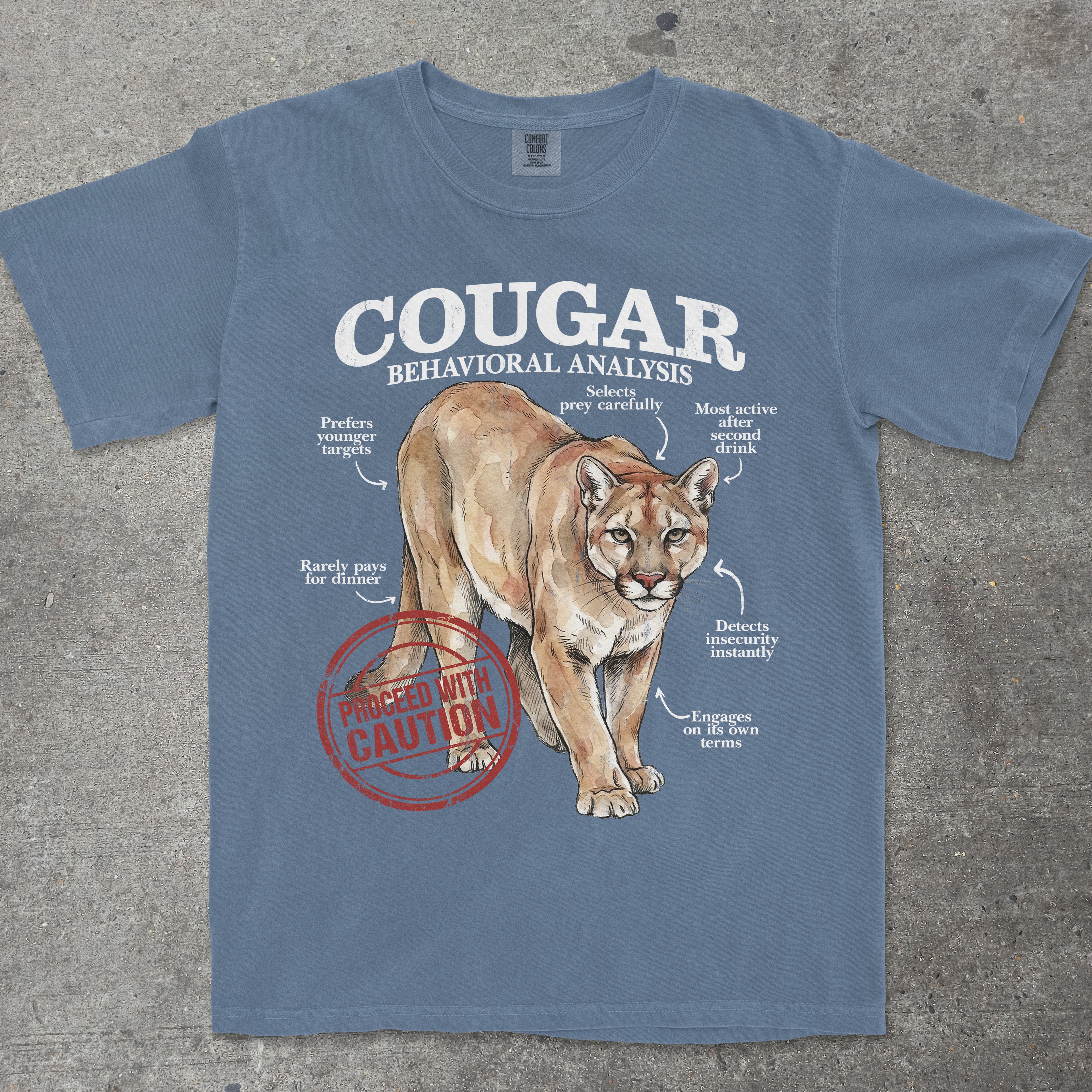Blue t-shirt with a cougar graphic and text on a concrete surface
