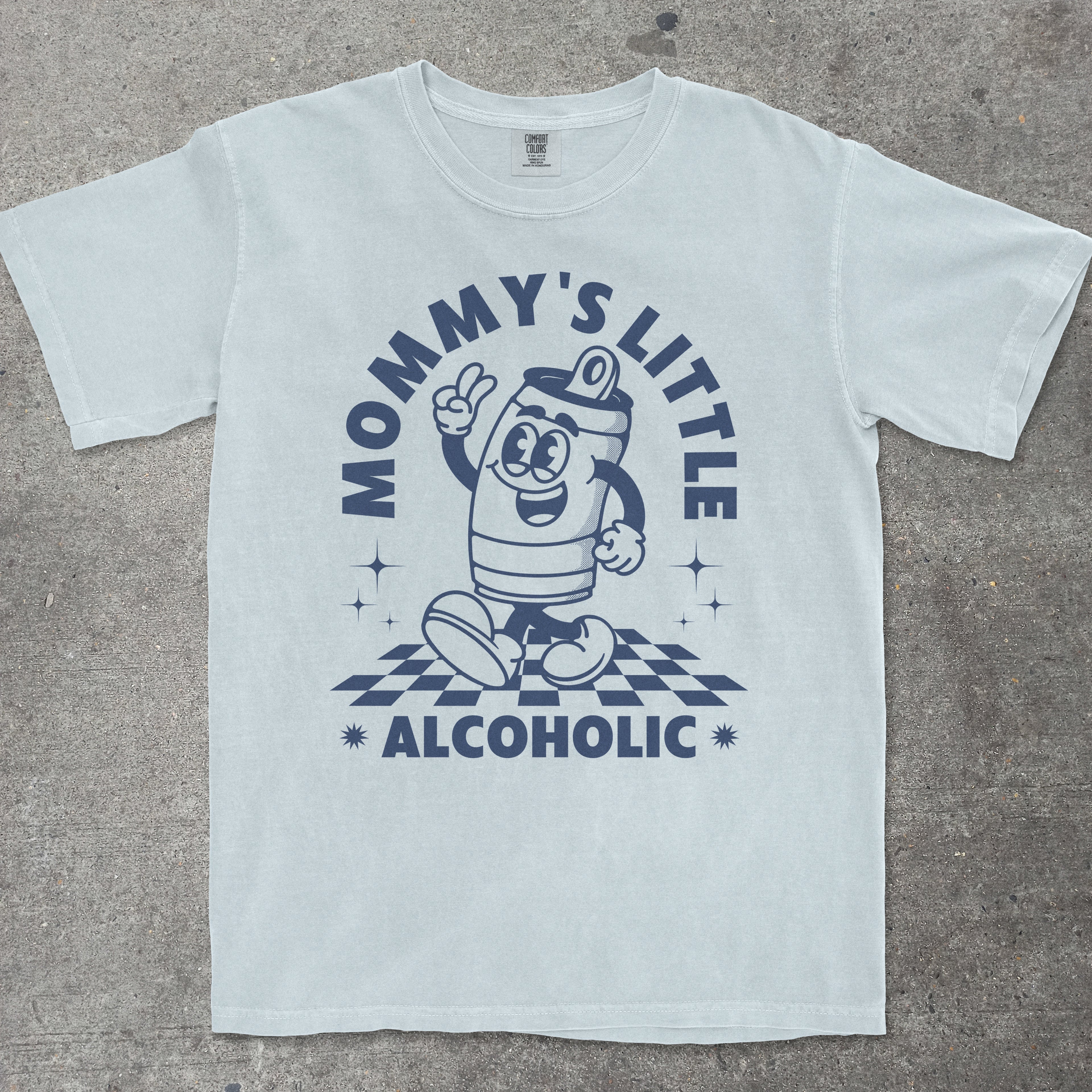 Light blue t-shirt with cartoon character and text 'Mommy's Little Alcoholic' on a gray surface