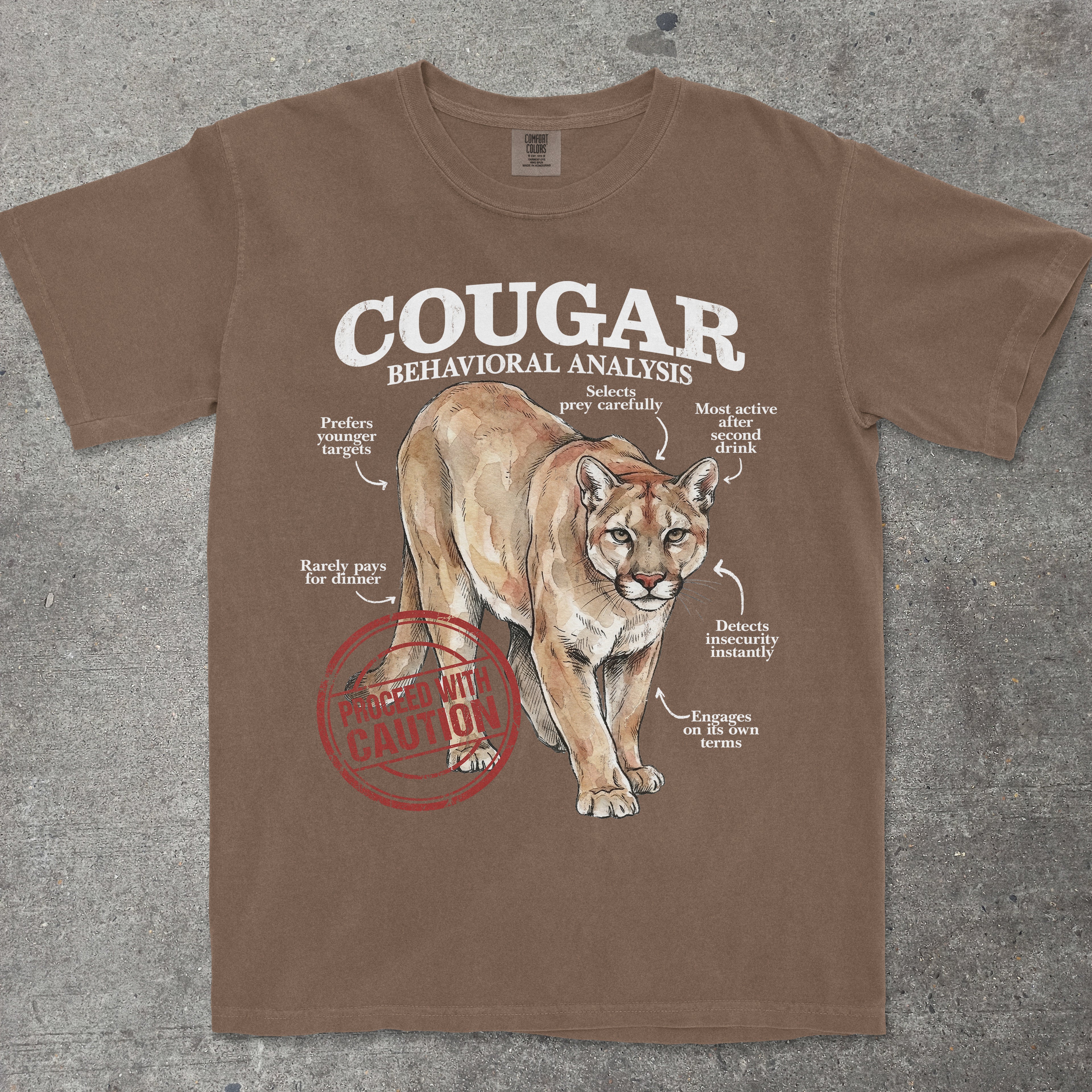 Brown t-shirt with a cougar graphic and text on a gray surface