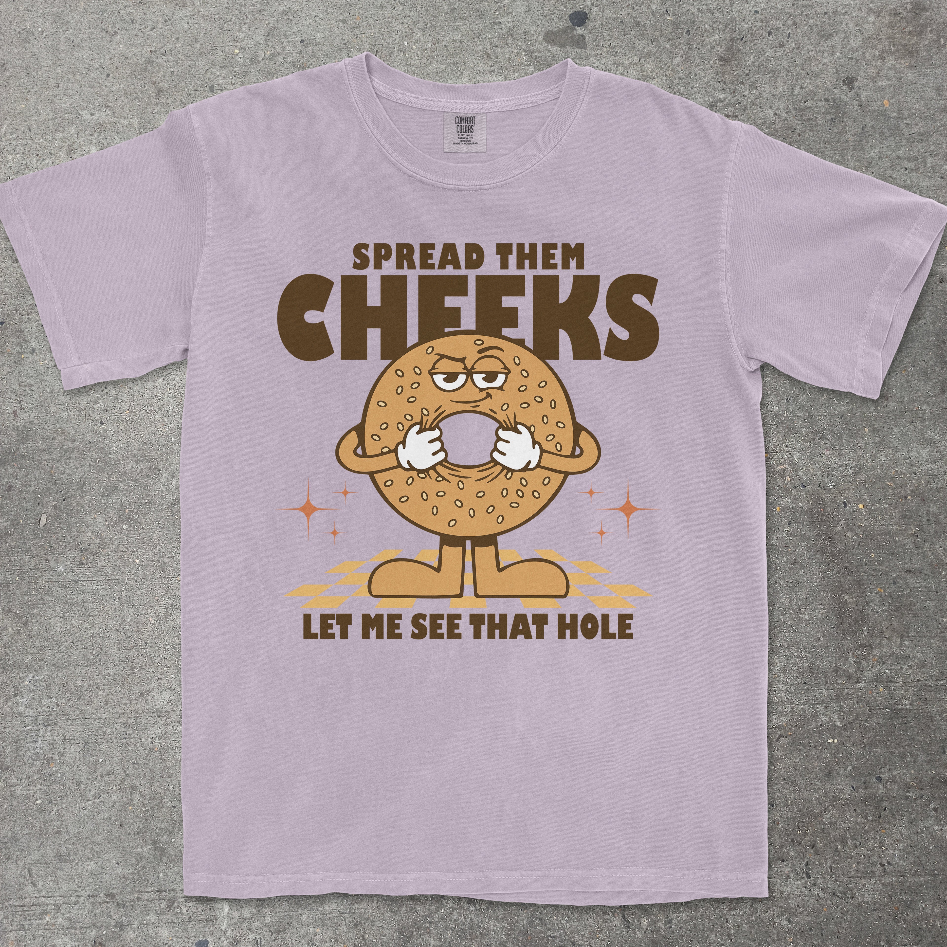 Purple t-shirt with a cartoon bagel graphic and humorous text on a gray background