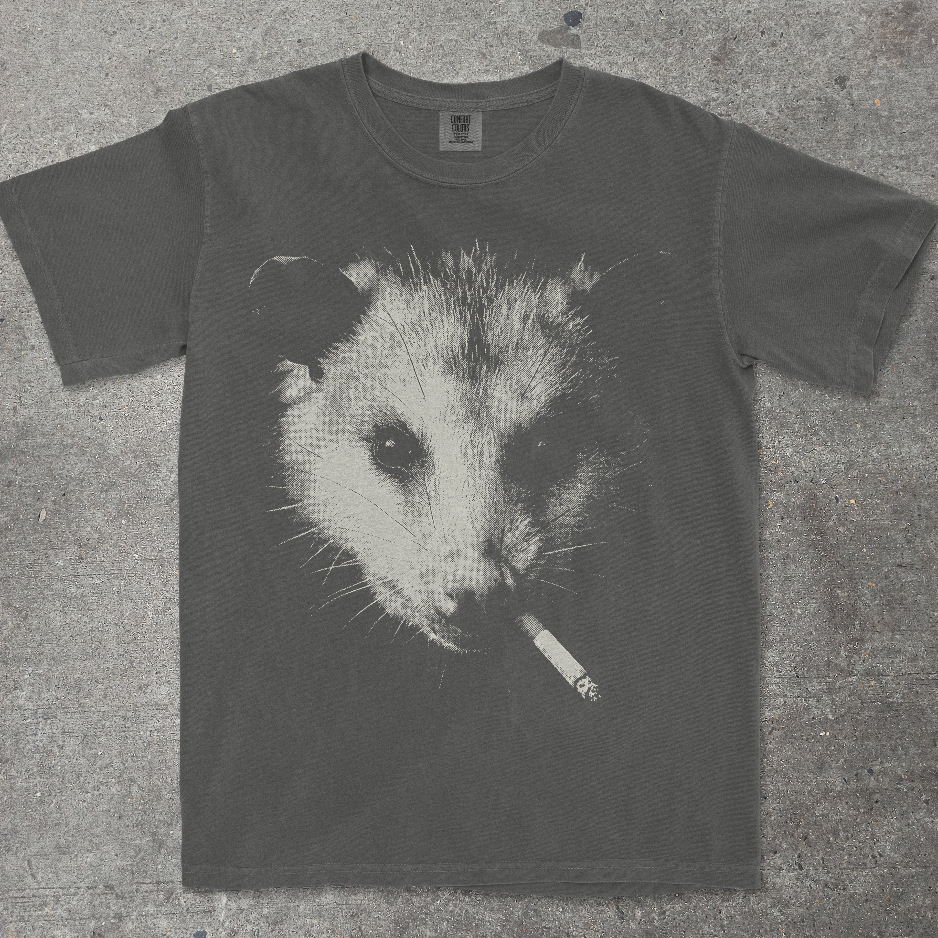 T-shirt with an opossum smoking a cigarette graphic on a textured surface