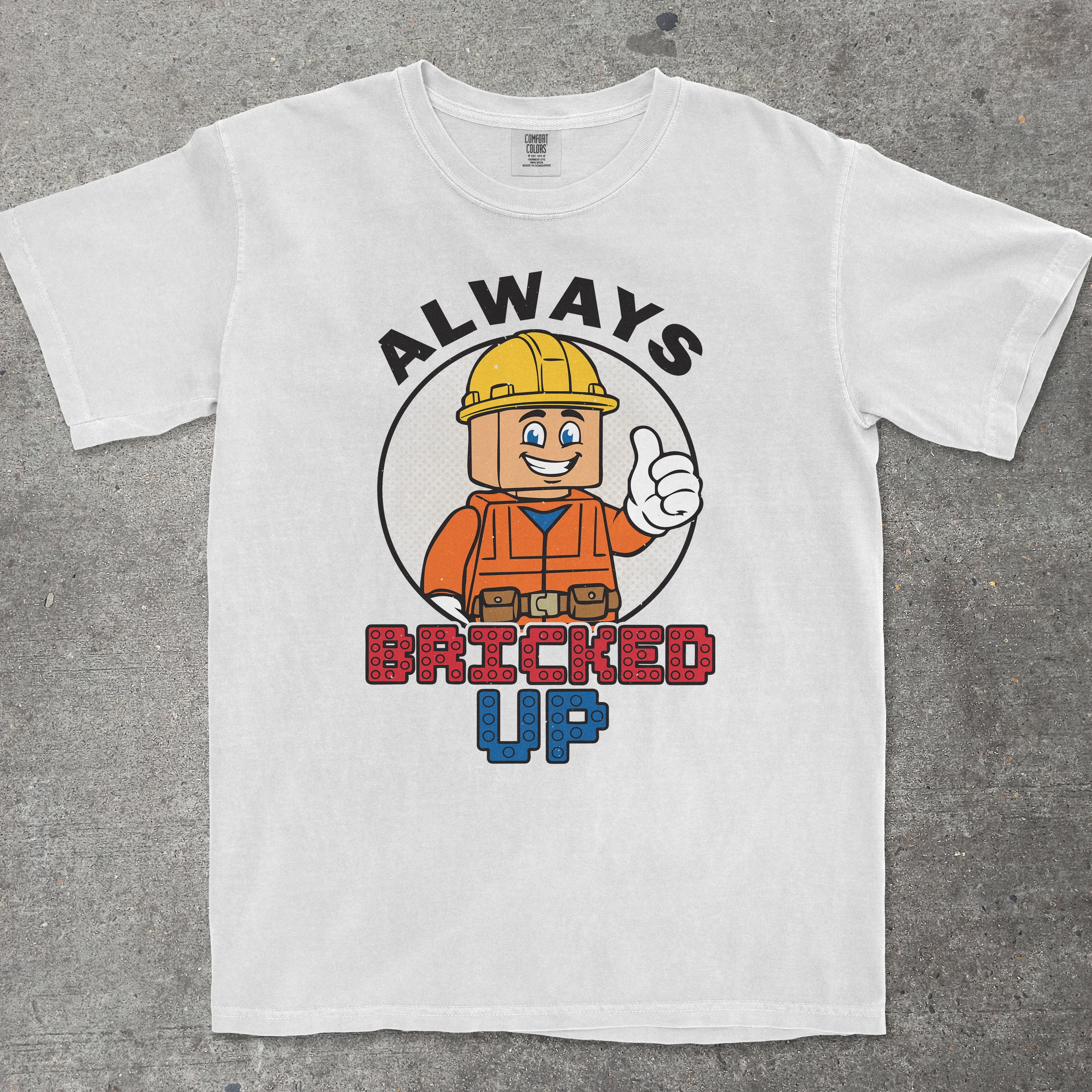 White graphic tee with "ALWAYS BRICKED UP" text and brick-themed mascot design by TeeHeeUSCo